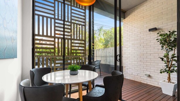 Eine moderne Terrasse mit rundem Tisch, vier Stühlen, einem Blumentopf und einem Holzdeck.