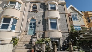 Un edificio en esquina con fachada de piedra, una puerta verde y un balcón.
