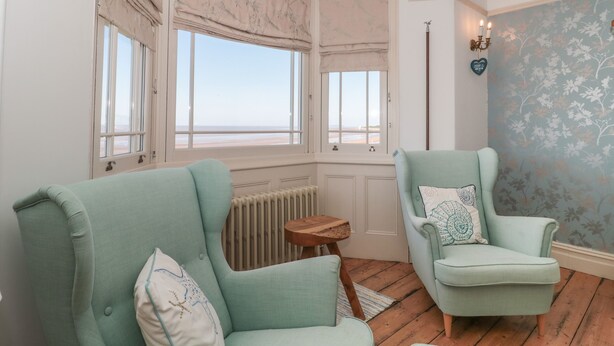 Una habitación con dos sillones azul claro, una mesita de madera y un radiador.