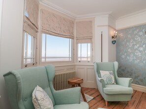 Una habitació amb dues butaques blavoses, una taula de fusta petita i un radiador.