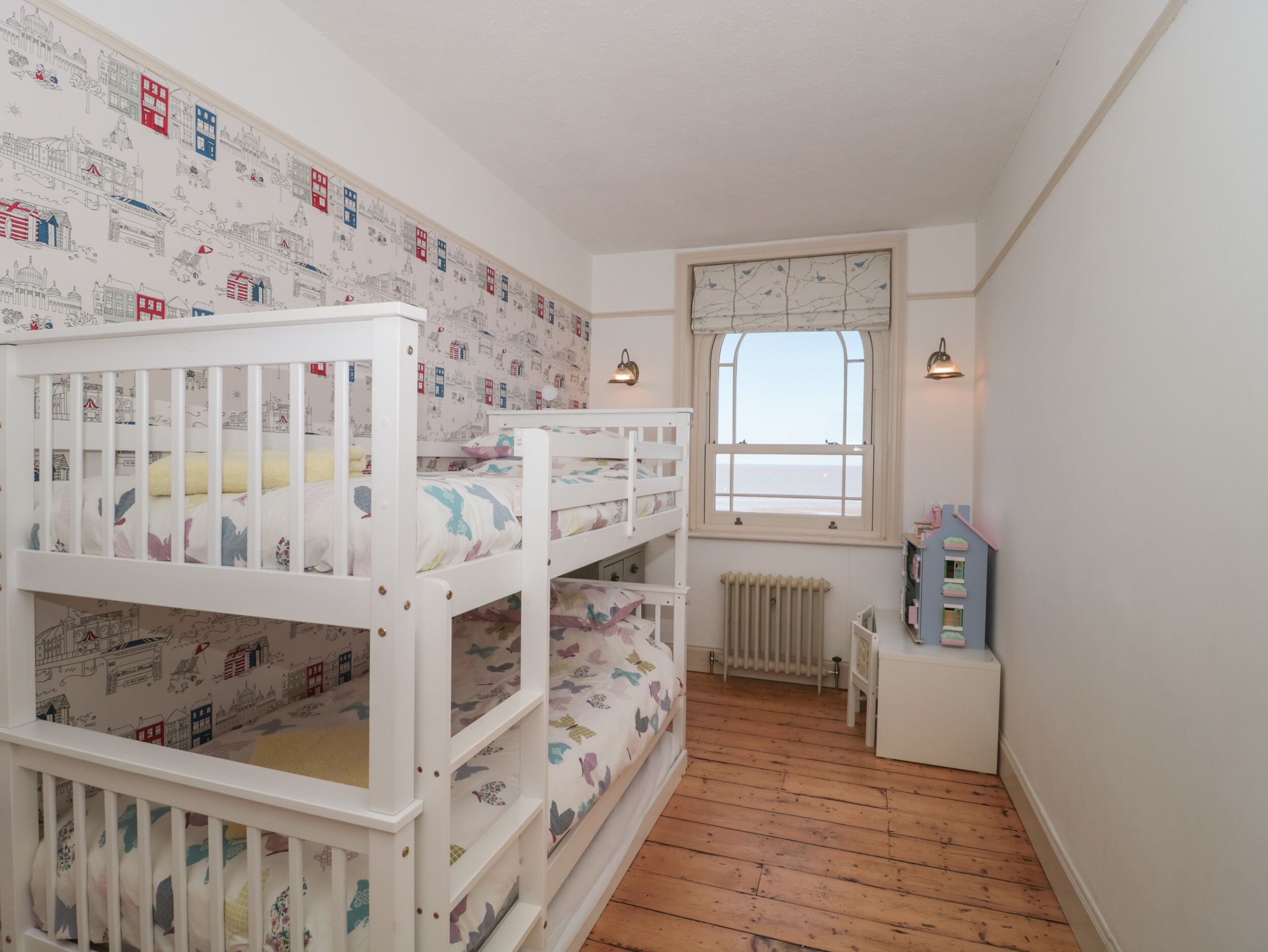 Un dormitorio infantil con literas, una ventana con vistas y un radiador.