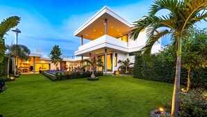 Une maison moderne à deux étages, dotée d’une pelouse bien entretenue, d’une piscine et d’un grand espace patio.