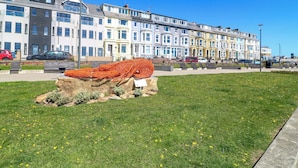 A row of terraced houses with a grassy area and a rock feature in the foreground. - Apt 10 @ Hunter's Quay (Bridlington)
