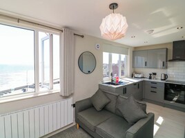Una cocina moderna con vistas al mar, un sofá gris y una lámpara colgante.