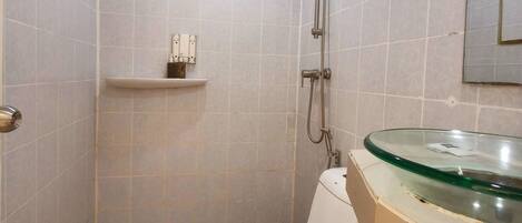 Ein Badezimmer mit Toilette, Dusche und einem Waschbecken aus Glas.
