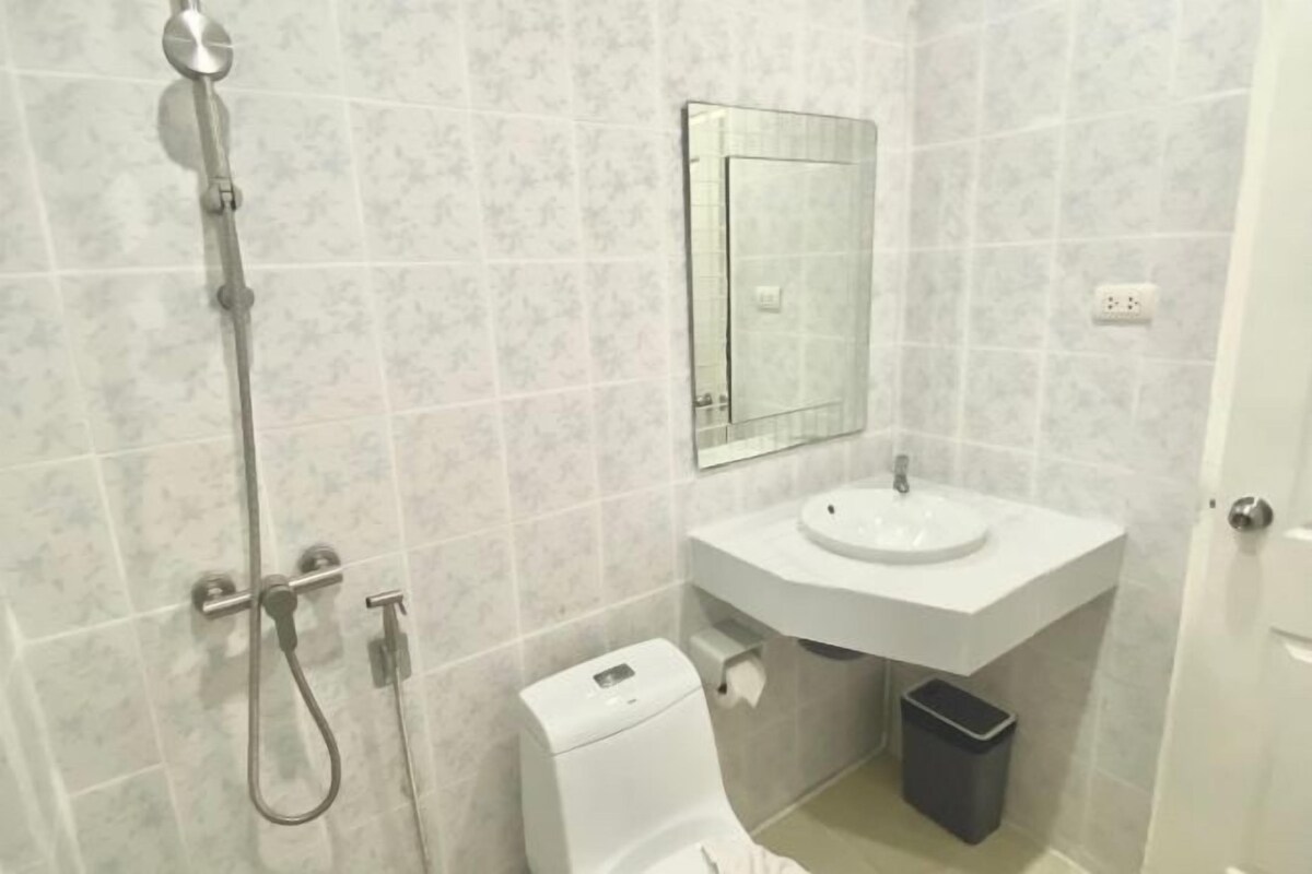 A bathroom with a shower, toilet, sink, and a mirror.