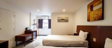 A hotel room with two beds, a desk, a chair, and a coat rack.