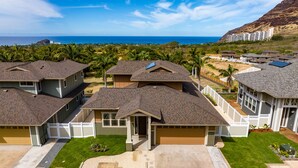 A residential area with houses featuring sloped roofs, a garage, and a well-maintained lawn. - Amazing Ocean Views, Game Room & Modern Design | Aloha Breeze 932 by AvantStay (Waianae)
