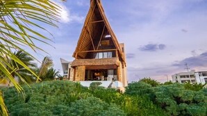 Un bâtiment moderne doté d’une structure de toit triangulaire, entouré d’une végétation luxuriante.
