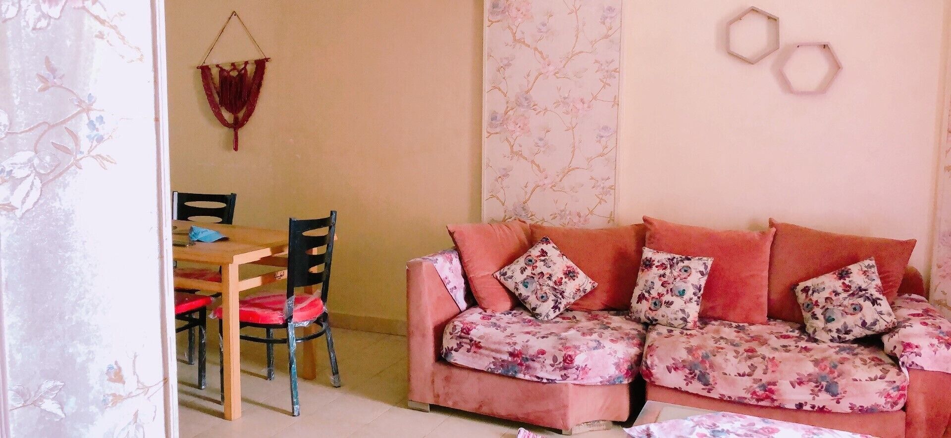 Una sala acogedora con un sofá floral, una mesa de comedor de madera y sillas.