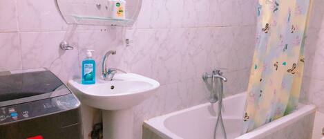 A bathroom with a white sink, a mirror, a shower with a curtain, and a toilet.