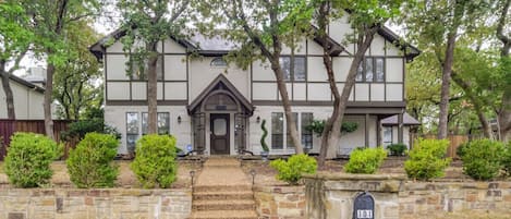 A two-story house with a stone entrance, a mailbox, and a well-maintained lawn.