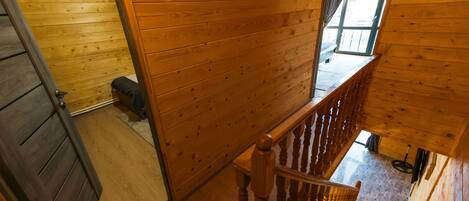 A wooden interior with a staircase, a door, and a window.