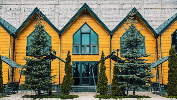 A yellow wooden building with a symmetrical facade, multiple windows, and a central entrance.