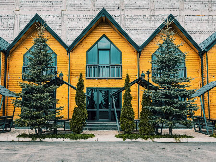 A yellow wooden building with a symmetrical facade, multiple windows, and a central entrance.