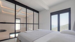 A modern bedroom with a large bed, a sliding glass door, and a view of the outdoors. - Seaview Villa with pool Vanja (Podostrog)