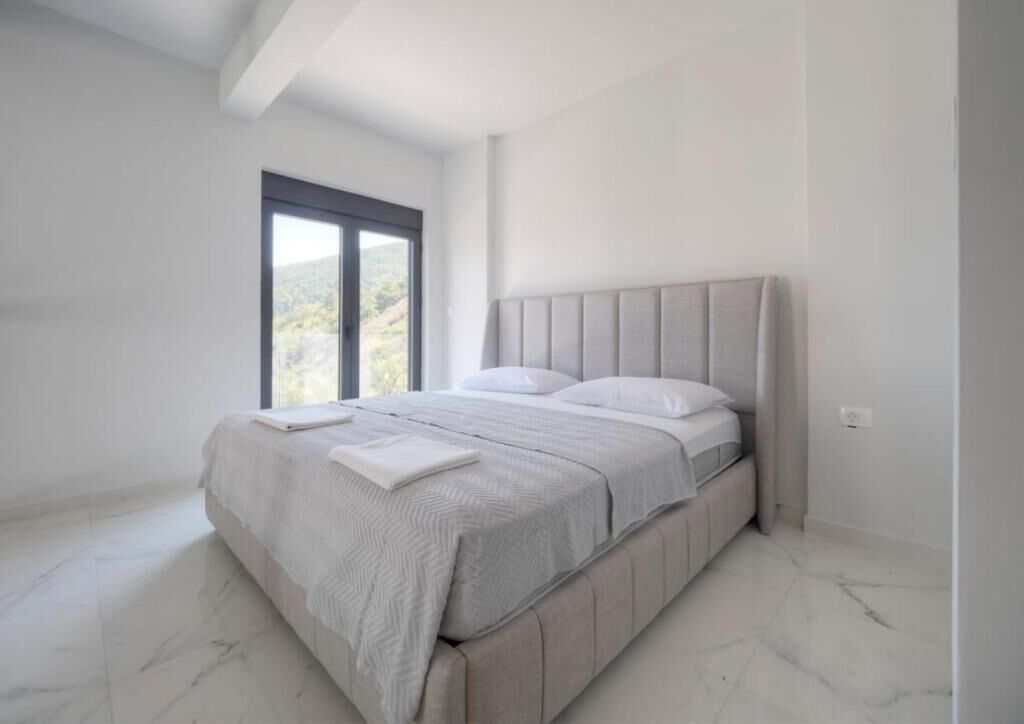 A modern bedroom with a large bed, a window, and a view of the outdoors.