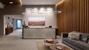 A modern reception area with a marble counter, wooden paneling, and a large landscape painting.