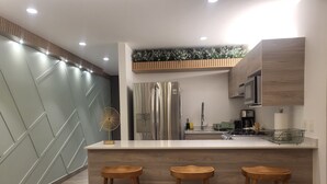 A modern kitchen with a central island, stainless steel appliances, and wooden bar stools.