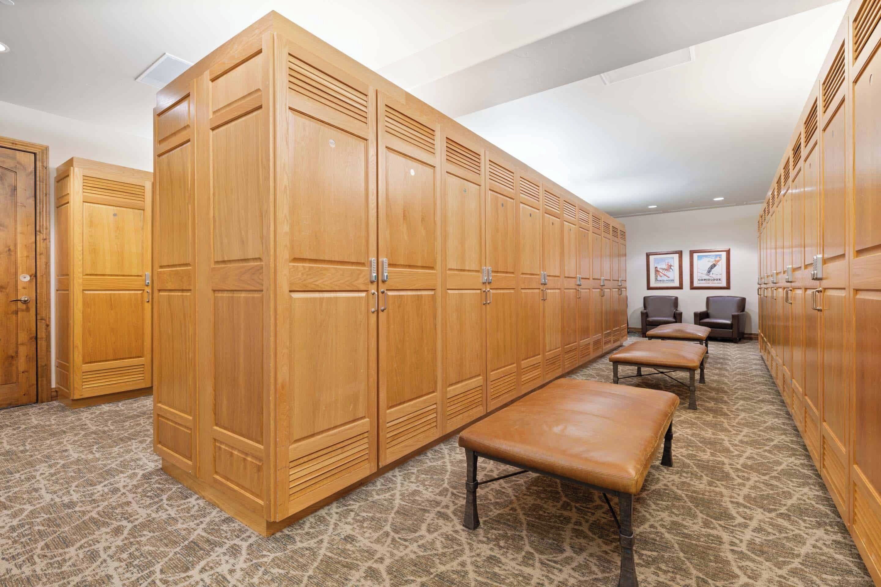 A row of wooden lockers with benches in a hallway.