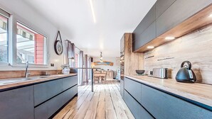 A modern kitchen with a wooden floor, dark cabinets, and a view into the dining area. - Guiriden by Interhome (Loctudy)