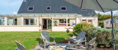 A house with a patio area featuring outdoor furniture and a large umbrella.