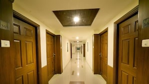 A hotel hallway with wooden doors numbered 303 and 30, leading to rooms. - HOTEL PLAZA INN (Coimbatore)