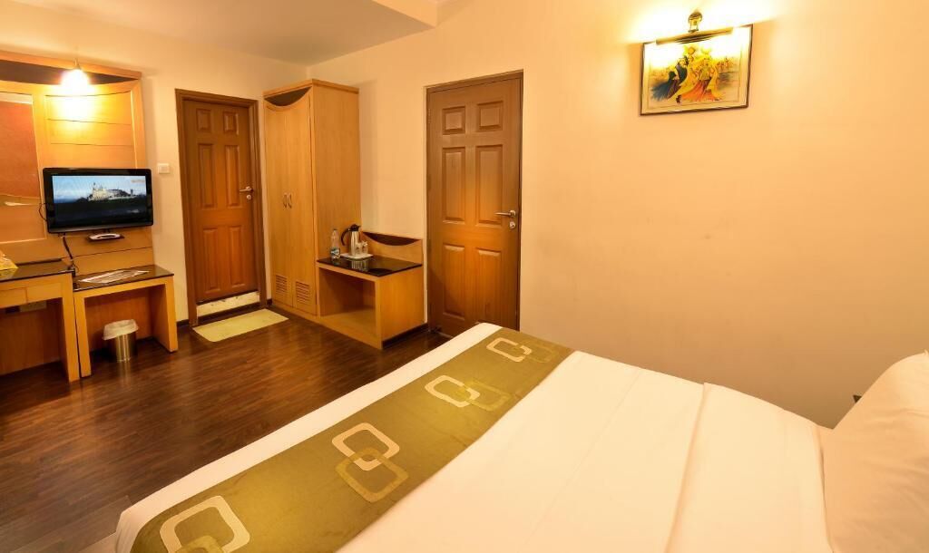 Una habitación de hotel con una cama, un escritorio con televisor, un armario y una puerta.