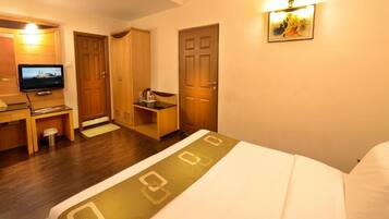 Una habitación de hotel con una cama, un escritorio con televisor, un armario y una puerta.