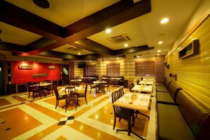Un restaurante con varias mesas y cabinas, un suelo con estampado y una pared de acento roja.