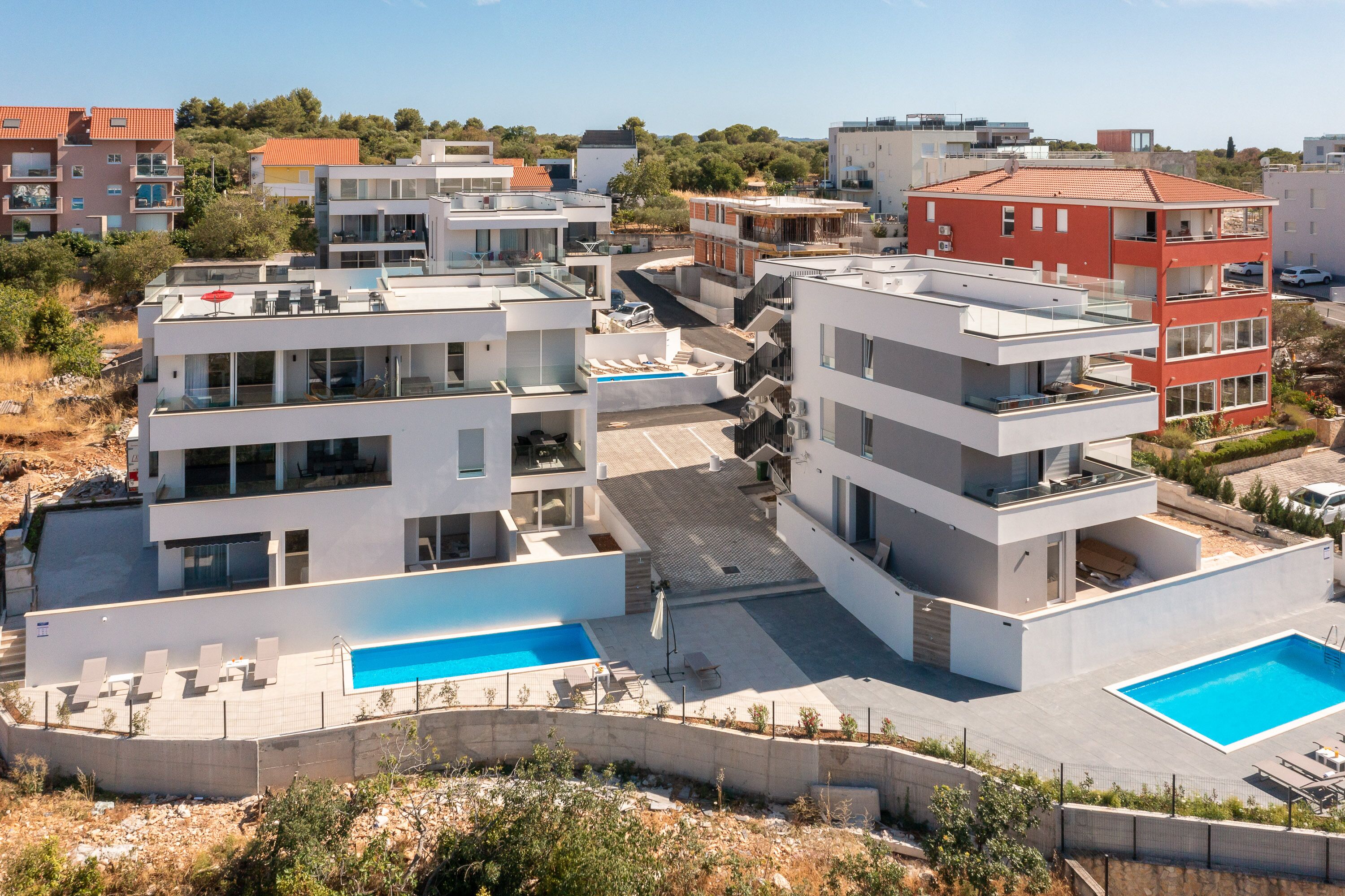 A modern residential building with multiple balconies, a rooftop pool, and a landscaped garden area.