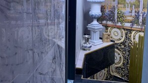 Un couloir doté d’un sol en marbre, d’un mur orné d’un motif noir et doré, et d’un élément décoratif blanc et doré.