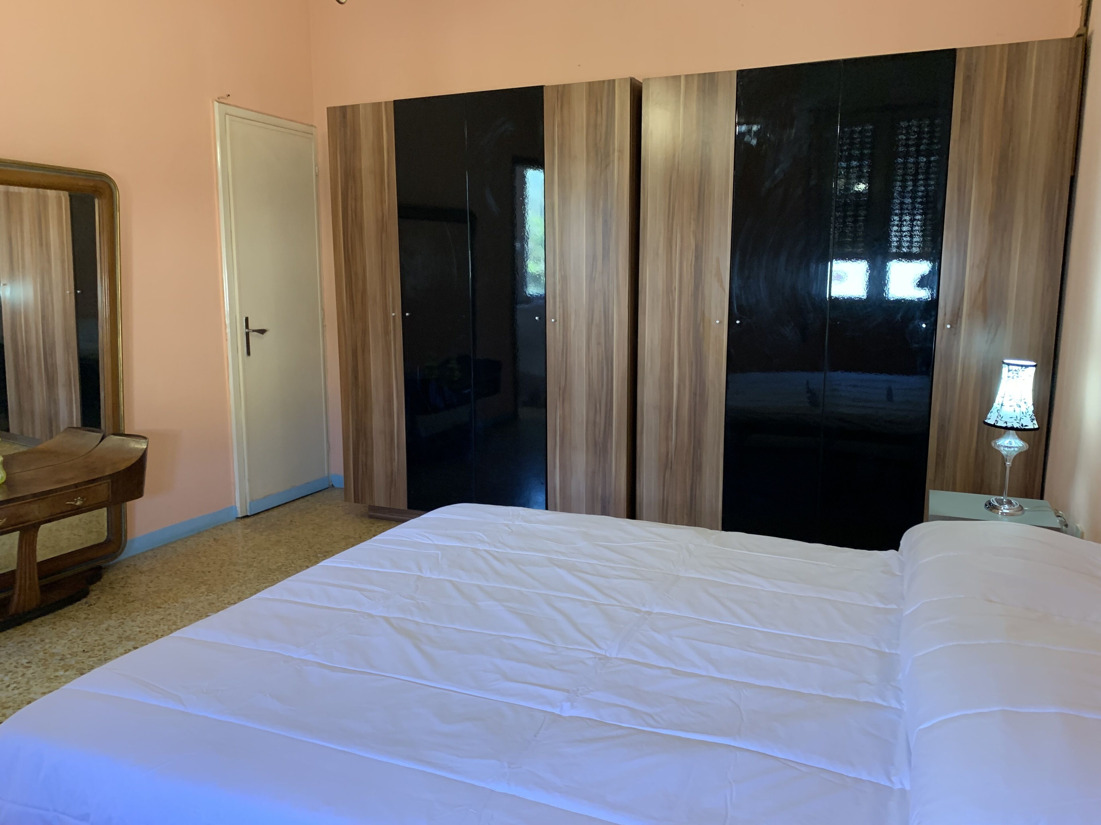 Ein Schlafzimmer mit einem Bett, einem Schminktisch, einem Spiegel und einer Tür.