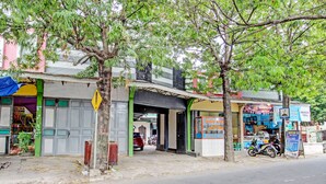 Vista de la calle con una fachada comercial, una motocicleta estacionada al frente y un árbol.