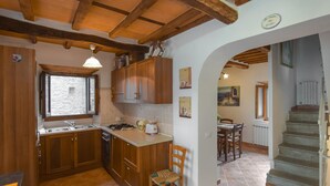 A kitchen with wooden cabinets, a built-in stove, and a dining area with a table and chairs. - Cozy home in Limano with WiFi (Limano)