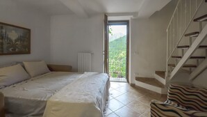 A bedroom with a bed, a radiator, a window, and a staircase. - Cozy home in Limano with WiFi (Limano)