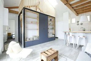Een moderne keuken met witte barkrukken, een houten kist en een blauwe accentmuur.