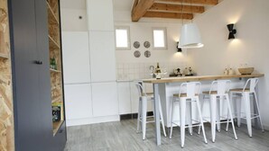Een moderne keuken met witte kastjes, een houten aanrecht en barstoelen.