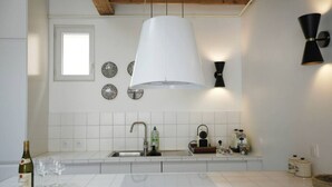 Een moderne keuken met witte tegels, een grote hanglamp, een raam en een spoelbak.