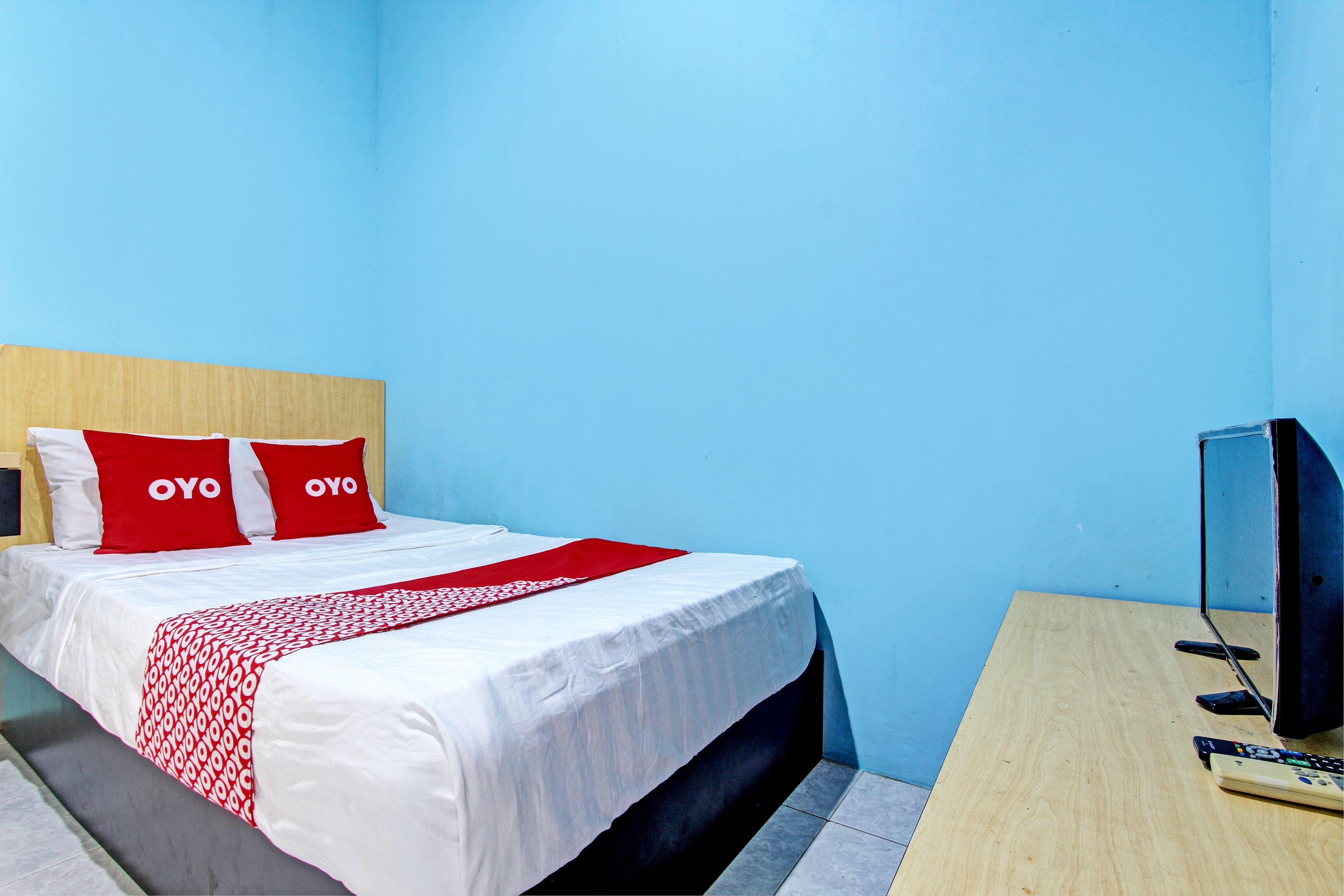 Una habitación de hotel con una cama, un televisor y un escritorio.