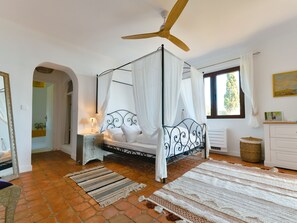 Cozy retreat with a four-poster bed, wooden ceiling fan, and a large window with curtains.
