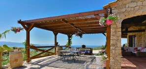 Relax in the serene patio area surrounded by lush greenery and a scenic view.