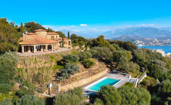 Relax by the pool surrounded by lush greenery and enjoy panoramic views of the coastline and distant mountains.