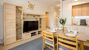 Une cuisine moderne dotée d’un téléviseur encastré, de meubles en bois et d’un coin repas avec une table mise pour deux personnes.