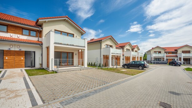Un quartier résidentiel moderne avec des maisons dotées de toits en tuiles rouges, des allées pavées et des voitures garées.