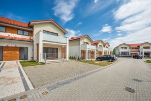 A modern residential area with houses featuring red-tiled roofs, paved walkways, and parked cars. - Sun & Snow Bursztynowa Polana (Ustka)