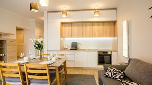Une cuisine compacte avec des meubles en bois, un four encastré et un coin repas avec une table dressée pour quatre personnes.