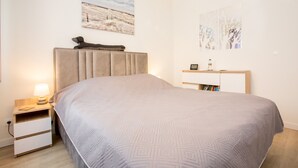 Une chambre bien rangée, avec un lit, des tables de chevet, une lampe et des œuvres d’art accrochées aux murs.