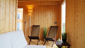 A wooden interior with two wicker chairs, a white sofa, and a small table. - Modernes Ferienhaus mit Kamin, Garten und Eigener Sauna - Ferienhaus Meerfreude (Vaschvitz)