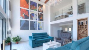 A spacious living room with a large window, a blue sofa, a white coffee table, and a bookshelf. - Seaview Villa with pool Hanja (Podostrog)